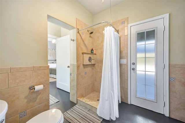 bathroom featuring toilet, a stall shower, and tile walls