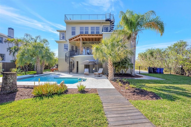 rear view of property featuring a lawn, a ceiling fan, a balcony, stairway, and fence