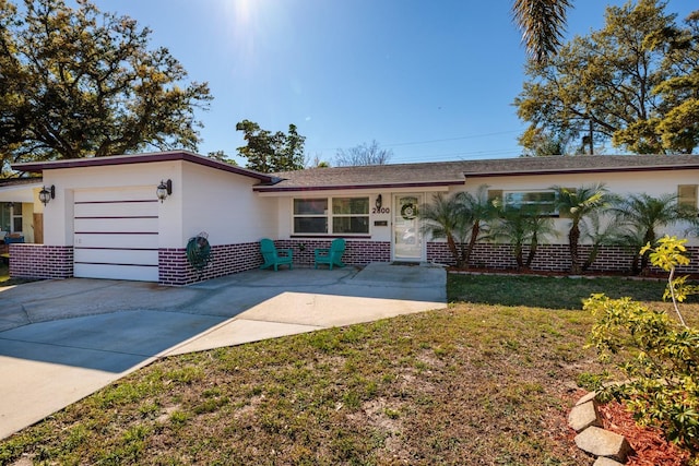 single story home with a front yard, an attached garage, brick siding, and concrete driveway