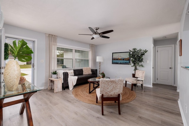 living room with light wood-style floors, baseboards, and ceiling fan