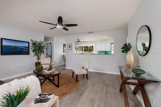 living area featuring visible vents, ceiling fan, baseboards, and wood finished floors