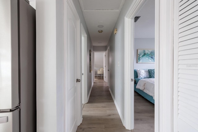 hallway featuring visible vents, baseboards, and light wood-style floors