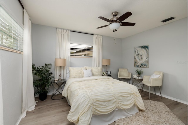 bedroom featuring multiple windows, visible vents, light wood-type flooring, and baseboards