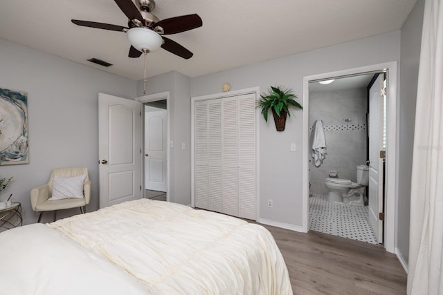 bedroom with visible vents, ensuite bath, wood finished floors, a closet, and baseboards