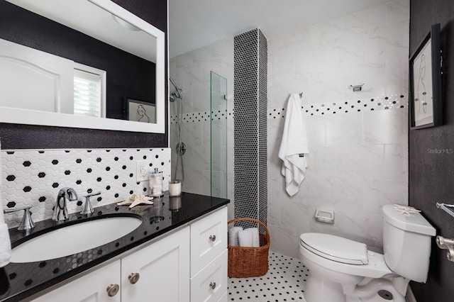 bathroom featuring toilet, tile walls, vanity, and a tile shower