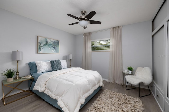 bedroom featuring baseboards, light wood finished floors, and ceiling fan