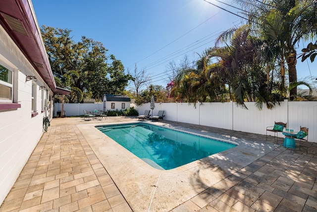 view of pool featuring a fenced in pool, a shed, a fenced backyard, an outbuilding, and a patio