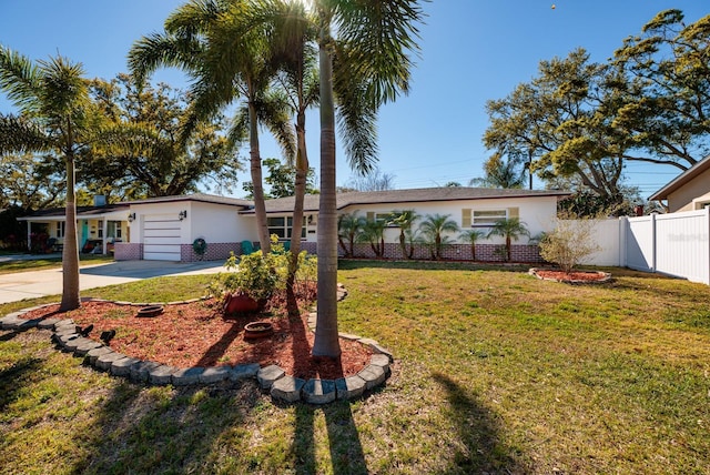 ranch-style house with concrete driveway, fence, brick siding, and a front yard