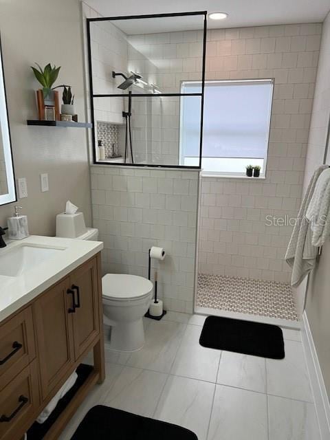 bathroom featuring toilet, tiled shower, tile patterned flooring, and vanity