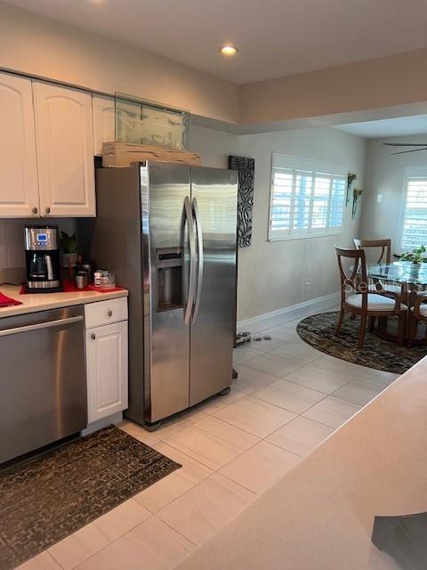 kitchen with light tile patterned floors, stainless steel appliances, white cabinetry, and decorative backsplash