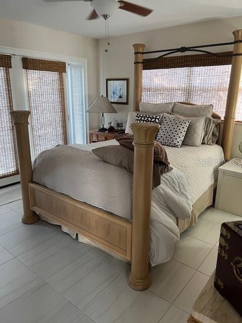 bedroom featuring ceiling fan, light tile patterned floors, and multiple windows