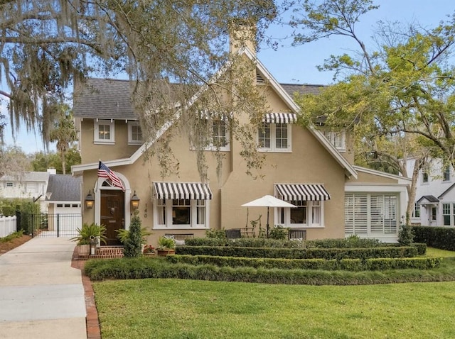 view of front of home featuring a shingled roof, fence, a front lawn, and stucco siding