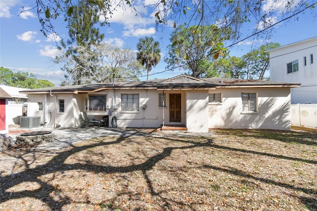 back of property with central air condition unit, a yard, a fire pit, and a patio area