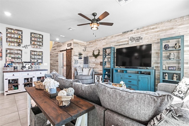 tiled living room with visible vents, ceiling fan, and a barn door