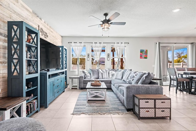 living area featuring light tile patterned floors, a ceiling fan, french doors, and a textured ceiling