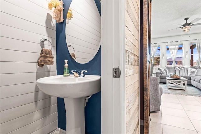 bathroom with tile patterned floors, wooden walls, and ceiling fan