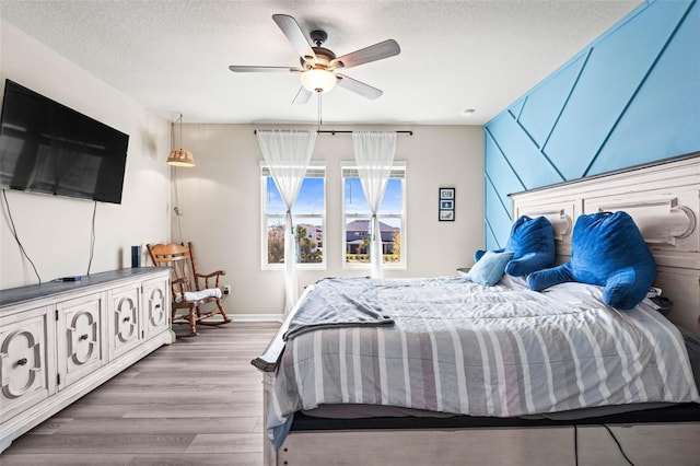 bedroom featuring a ceiling fan, wood finished floors, baseboards, and a textured ceiling