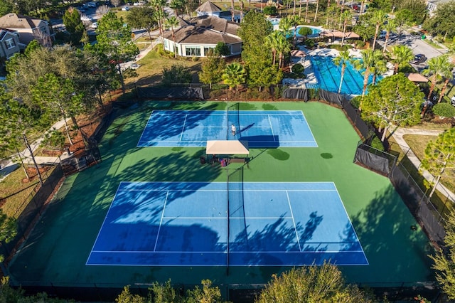 view of basketball court with a tennis court and fence