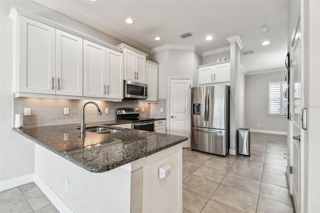 kitchen with kitchen peninsula, sink, tasteful backsplash, appliances with stainless steel finishes, and white cabinets