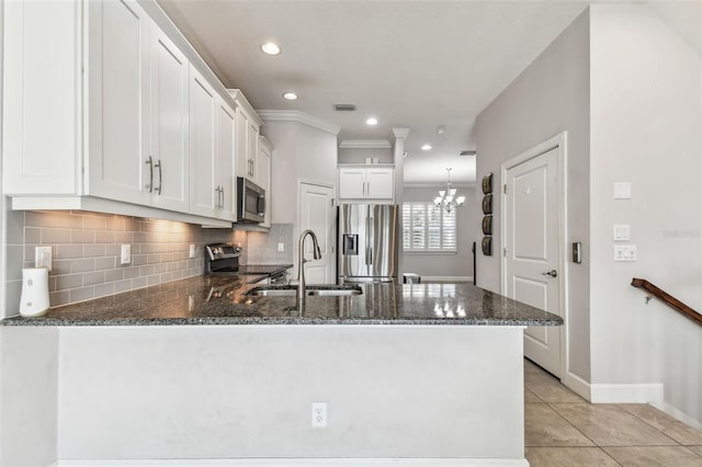 kitchen with sink, dark stone counters, stainless steel appliances, kitchen peninsula, and white cabinets