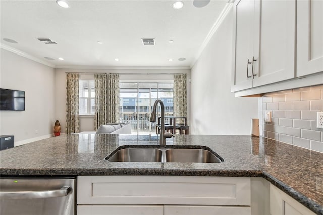 kitchen featuring sink, white cabinetry, dark stone counters, stainless steel dishwasher, and tasteful backsplash