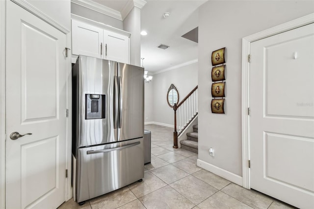 kitchen with white cabinets, light tile patterned floors, stainless steel fridge, and ornamental molding