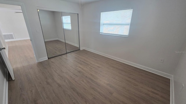 unfurnished bedroom featuring multiple windows, a closet, and dark hardwood / wood-style floors