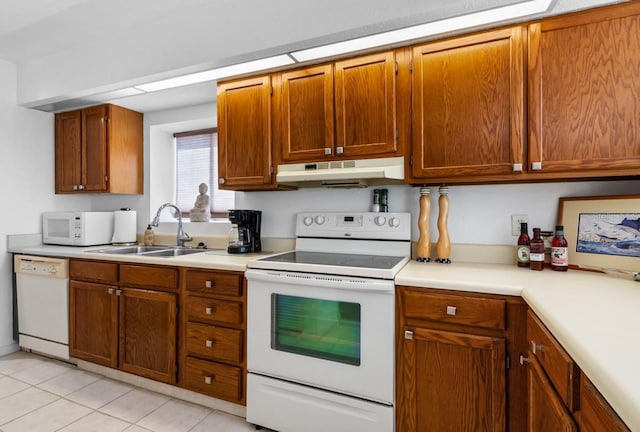 kitchen with a sink, under cabinet range hood, light countertops, white appliances, and brown cabinetry