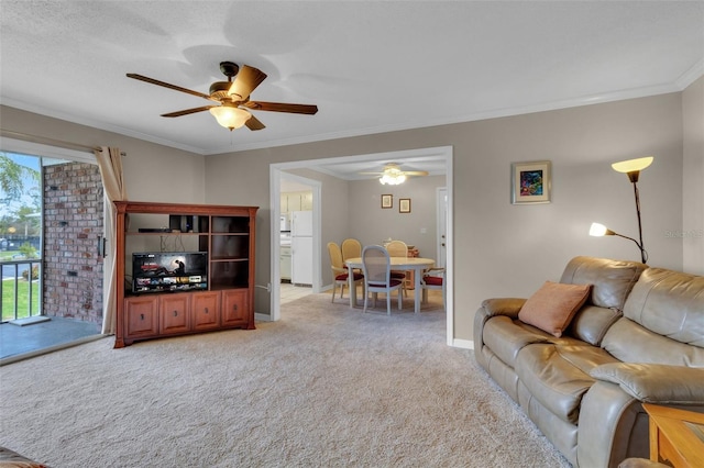 living area with ornamental molding, light colored carpet, baseboards, and a ceiling fan
