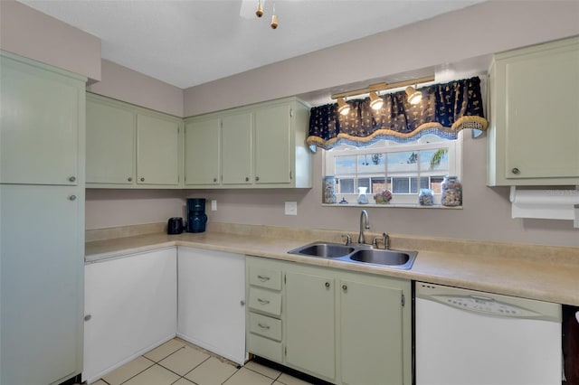 kitchen with light tile patterned floors, a sink, white dishwasher, light countertops, and green cabinetry