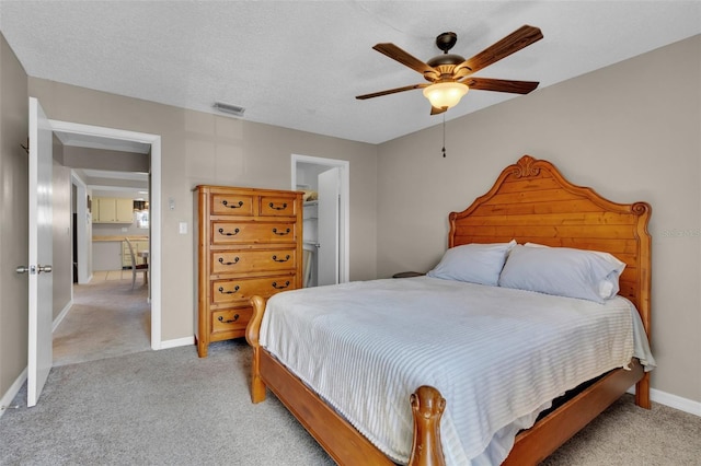 bedroom featuring visible vents, light carpet, ceiling fan, a textured ceiling, and baseboards