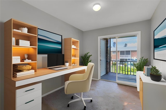carpeted office with built in study area and baseboards