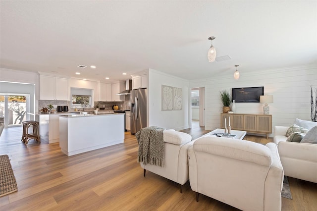 living room featuring crown molding, light wood finished floors, and recessed lighting