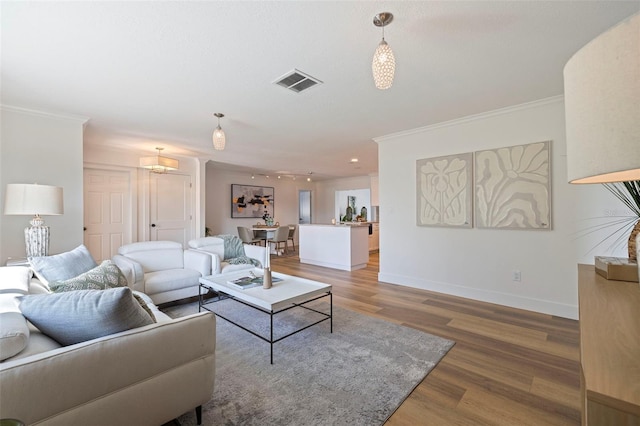 living room with baseboards, visible vents, wood finished floors, and crown molding