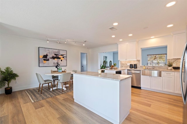 kitchen with a sink, white cabinets, dishwasher, and light wood-style floors