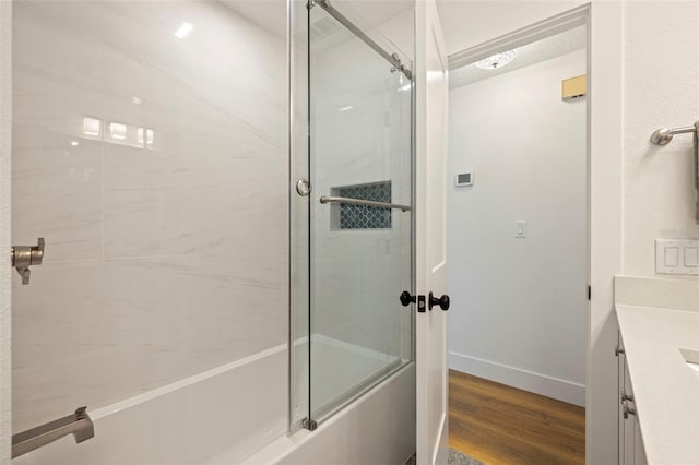 bathroom featuring vanity, bath / shower combo with glass door, wood finished floors, and baseboards