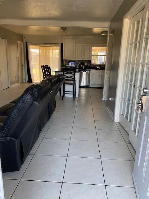 kitchen featuring dark countertops, a sink, stainless steel dishwasher, and light tile patterned floors