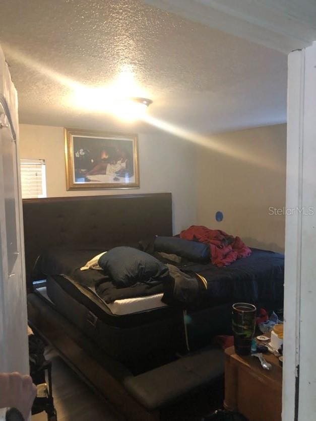 bedroom with a textured ceiling and wood finished floors