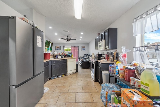 kitchen with stainless steel appliances, sink, ceiling fan, light tile patterned floors, and a textured ceiling