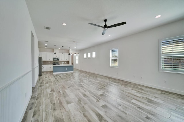 unfurnished living room featuring ceiling fan and light wood-type flooring