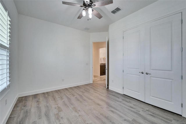 unfurnished bedroom featuring light hardwood / wood-style flooring, multiple windows, and a closet