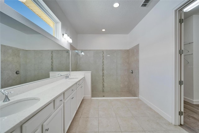 bathroom featuring tile patterned floors, tiled shower, a textured ceiling, and vanity