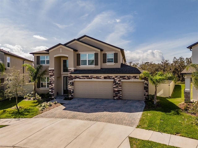 view of front of house featuring decorative driveway, stucco siding, a front yard, a garage, and stone siding