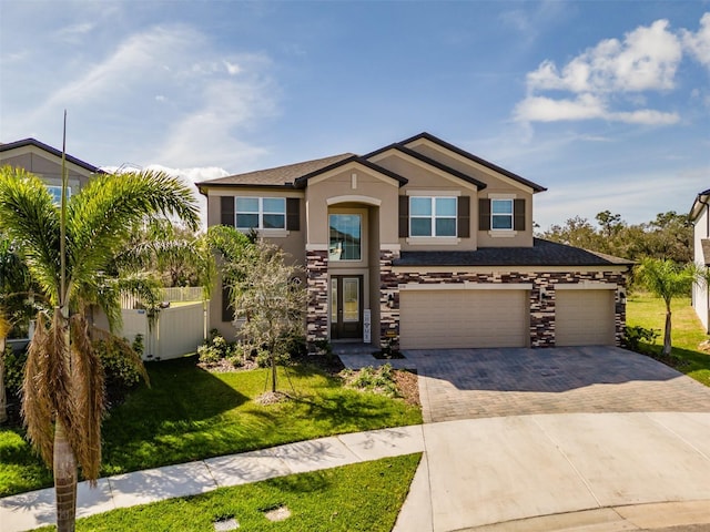 view of front of home featuring a garage, stucco siding, fence, decorative driveway, and a front yard