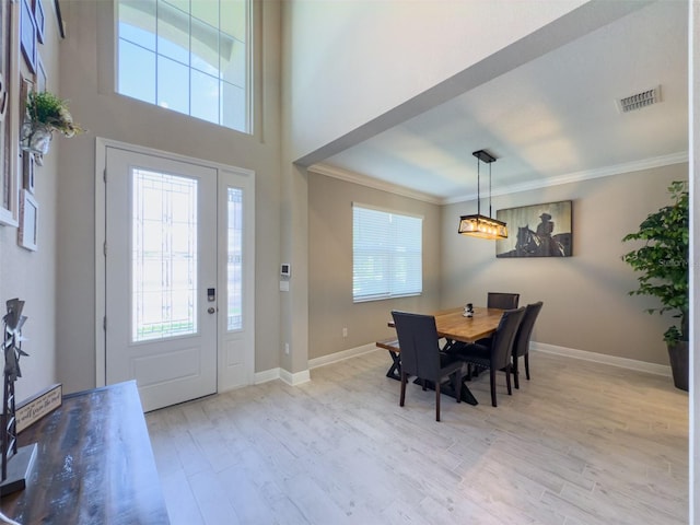 foyer entrance featuring baseboards, light wood-style flooring, visible vents, and crown molding
