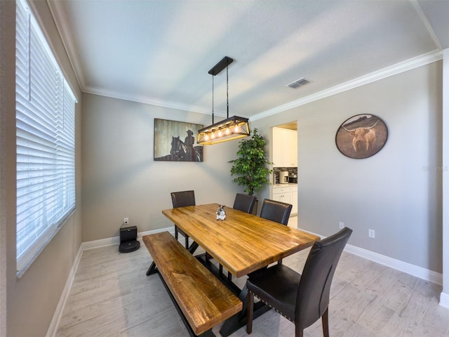 dining room with visible vents, crown molding, light wood-style flooring, and baseboards