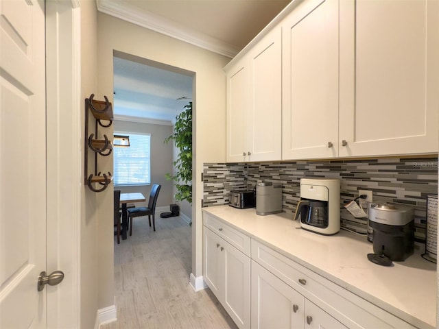bar with ornamental molding, light wood-type flooring, baseboards, and decorative backsplash