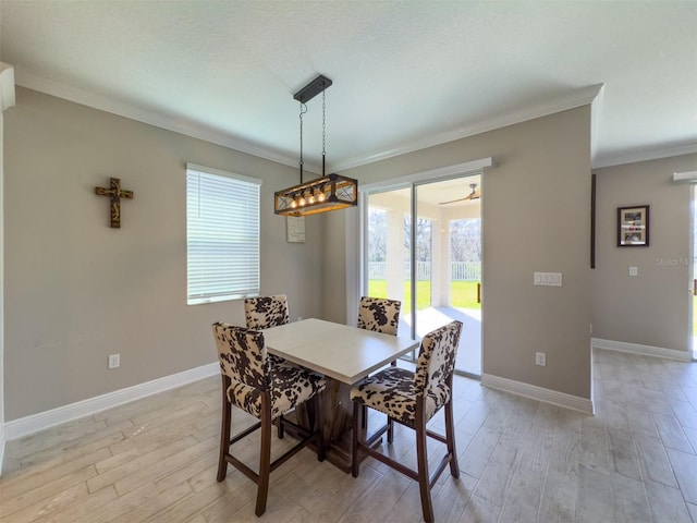 dining room with ornamental molding, light wood-type flooring, and baseboards