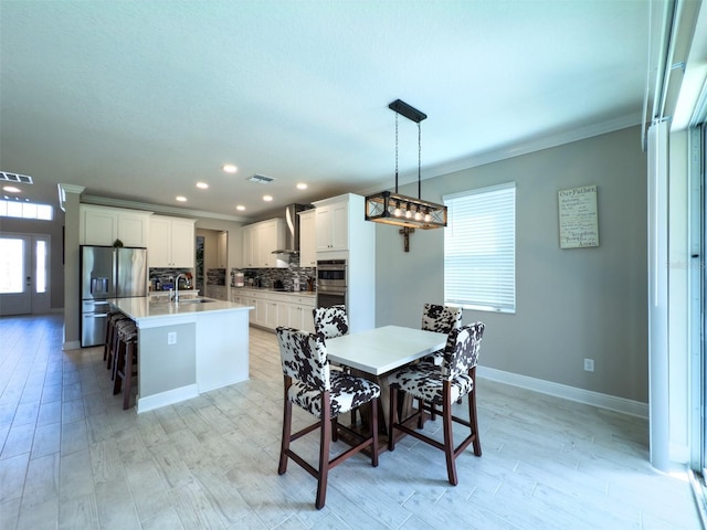 dining room with light wood finished floors, recessed lighting, visible vents, ornamental molding, and baseboards