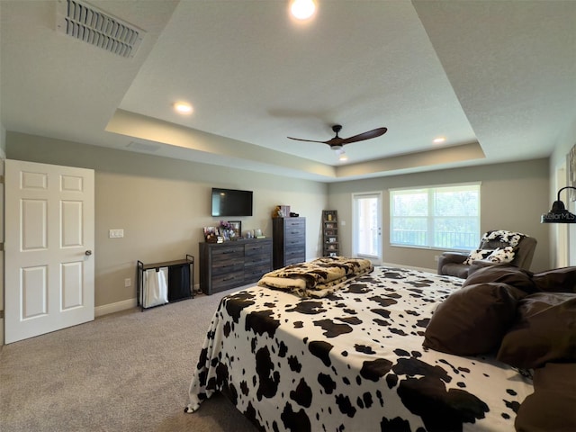 bedroom with a raised ceiling, light colored carpet, visible vents, a ceiling fan, and baseboards